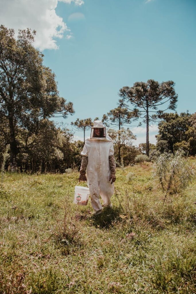 Women Standing on the Grass While Holding a Bucket